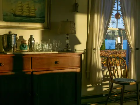 An old timber sideboard with glassware on it, in late sunlight by a window