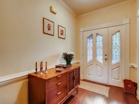 A timber sideboard in a hallway beside a pair of glazed front doors