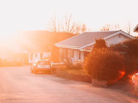 A brick house on a quiet suburban street at sunset
