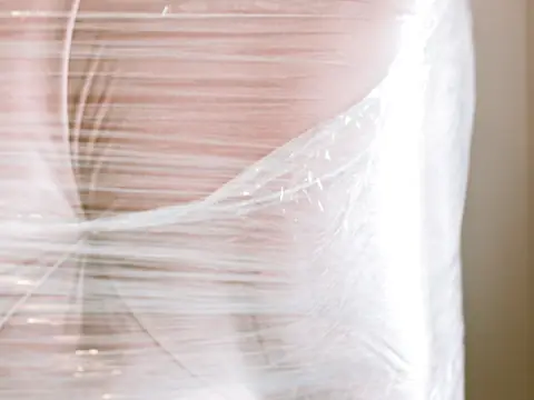 An upholstered chair wrapped tight in stretch film