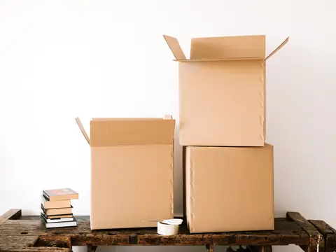Open and closed cardboard boxes with packing tape on a timber bench