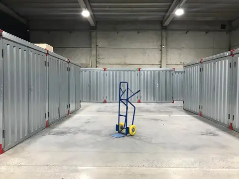 A row of metal storage units with a hand truck in the aisle