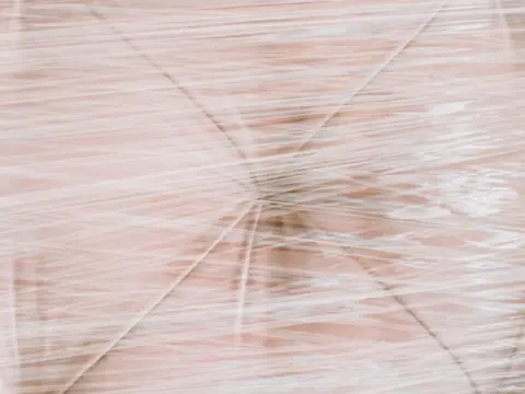 Stretch film wrapped over a buttoned upholstered piece, close up