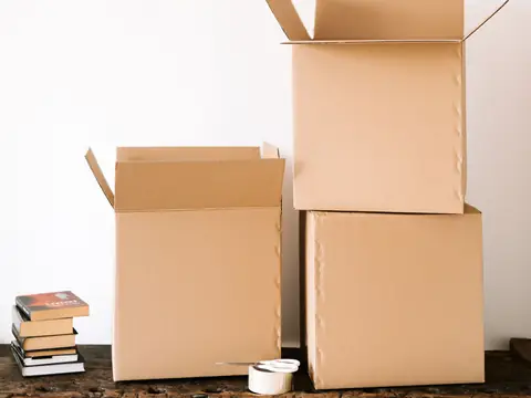 Cardboard boxes, a roll of tape and a stack of books on a timber bench