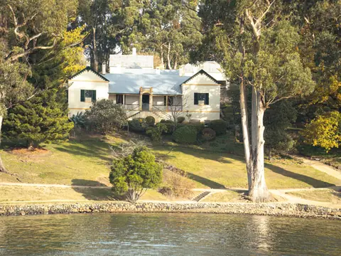 A white cottage among trees beside the water