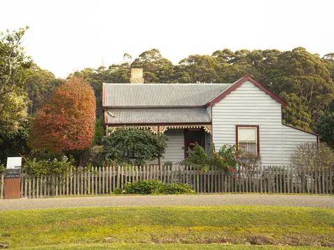 A weatherboard cottage behind a timber picket fence