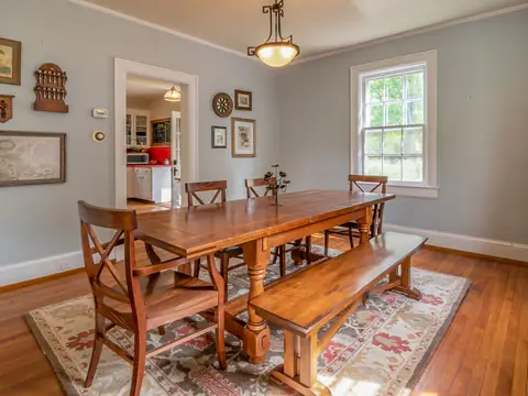 A dining room with a long timber table, chairs and a bench on a patterned rug