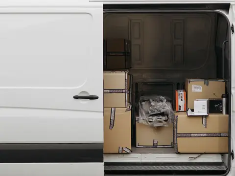 The open side door of a white van loaded with packed boxes